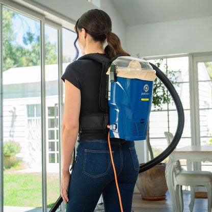 Person using a backpack vacuum cleaner in a home setting