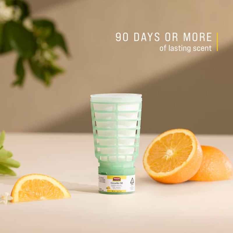 Green cylindrical container with oranges on a beige surface, featuring text about scent duration.