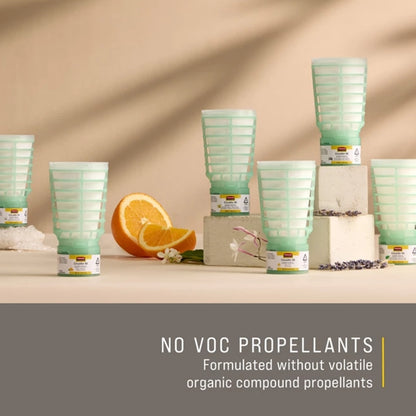 Green air freshener containers on a beige surface with an orange and flowers, labeled 'NO VOC Propellants'.