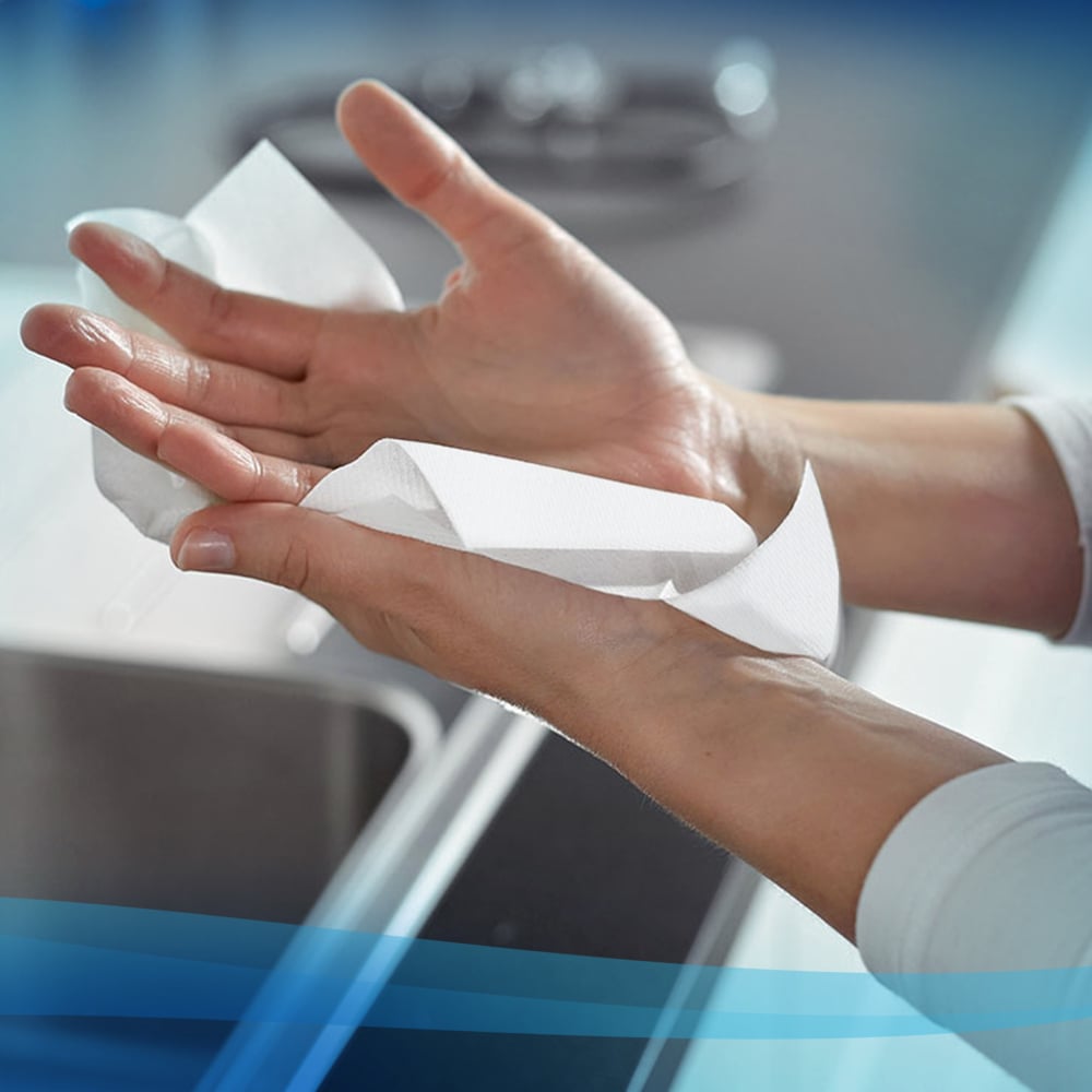 Person holding a Scott white paper towel with a blurred kitchen background