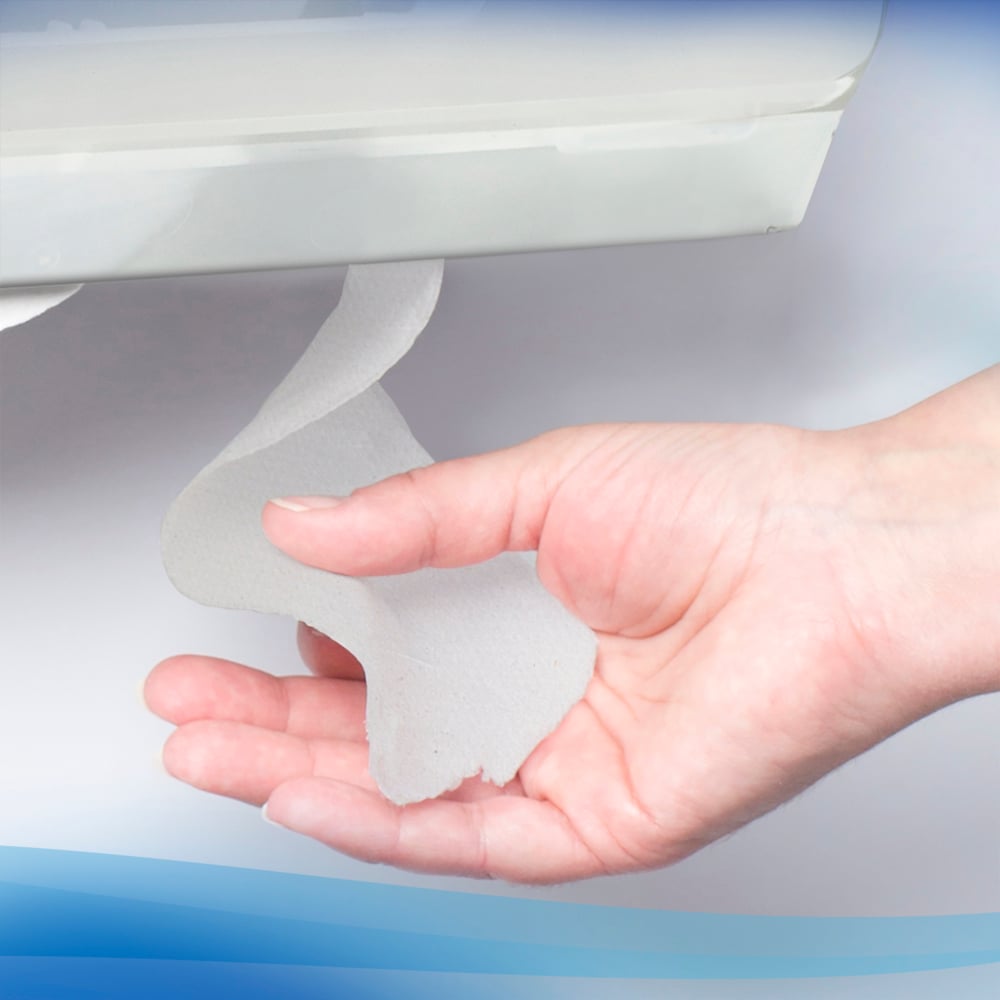 Hand holding a small piece of Scott Toilet Tissue against a blurred background