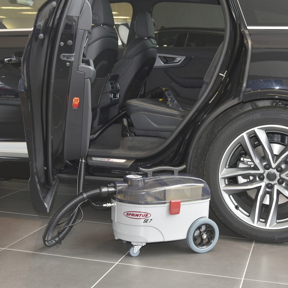 Car cleaning machine next to an open car door on a tiled floor