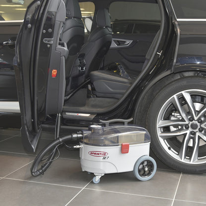 Car cleaning machine next to an open car door on a tiled floor