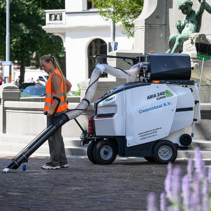 Person operating a large cleaning machine labeled 'Aria 240' in an urban setting.