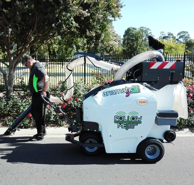 Person operating a TSM Ariamatic 240 on a road with trees and a fence in the background.