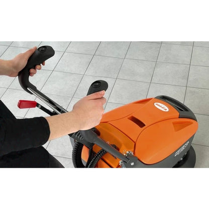 Person using an orange floor cleaning machine on a tiled floor
