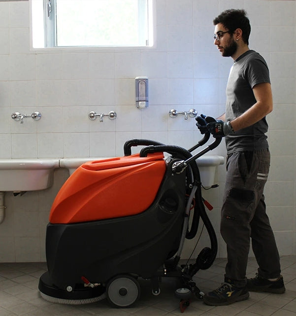 Person using a TSM Grande Brio 50B Scrubber Dryer machine in a bathroom setting
