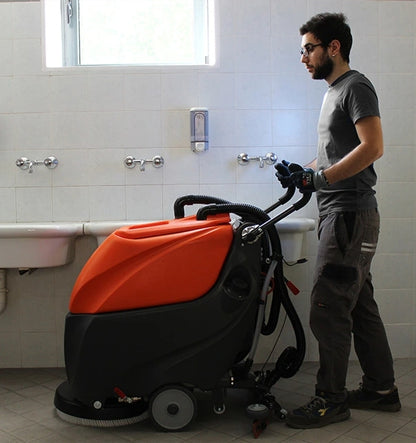 Person using a TSM Grande Brio 50B Scrubber Dryer machine in a bathroom setting