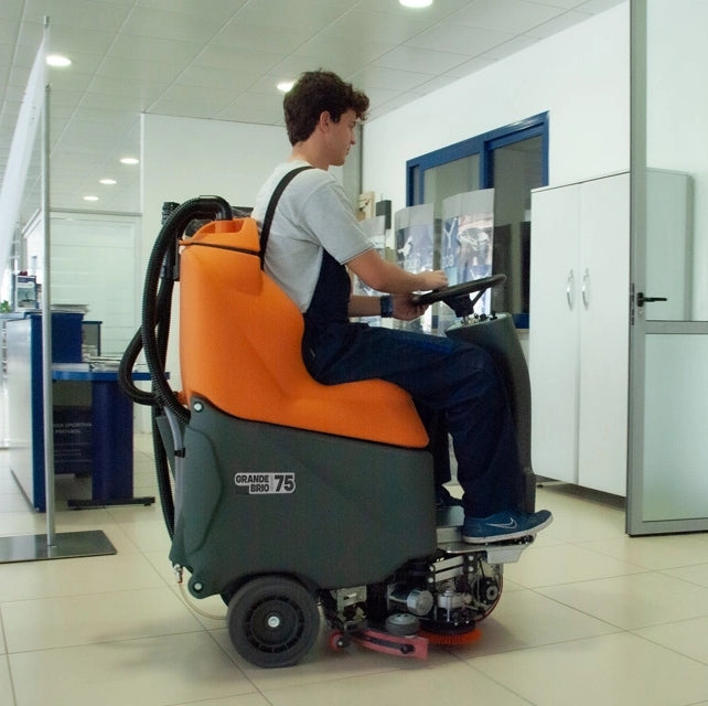 Person operating a TSM Grande Brio Ride On 75-650 Scrubber machine in an indoor setting