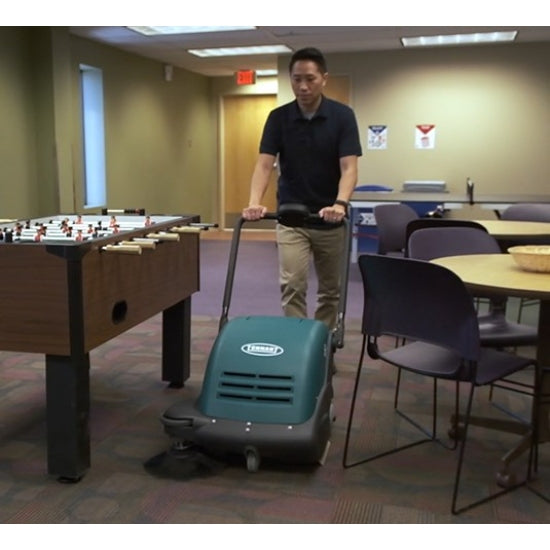Person pushing a Tennant S7 Battery Sweeper in a room with tables and chairs