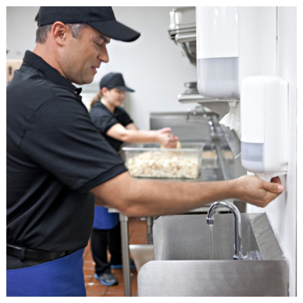 Person washing dishes in a kitchen setting with another person in the background