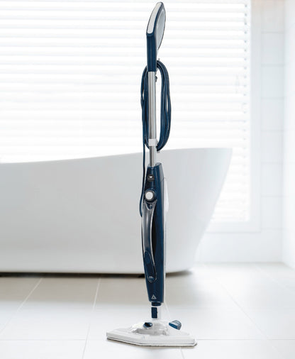 Blue and silver Wertheim Dual Steam Mop Plus on a white floor with a white wall and window blinds in the background.